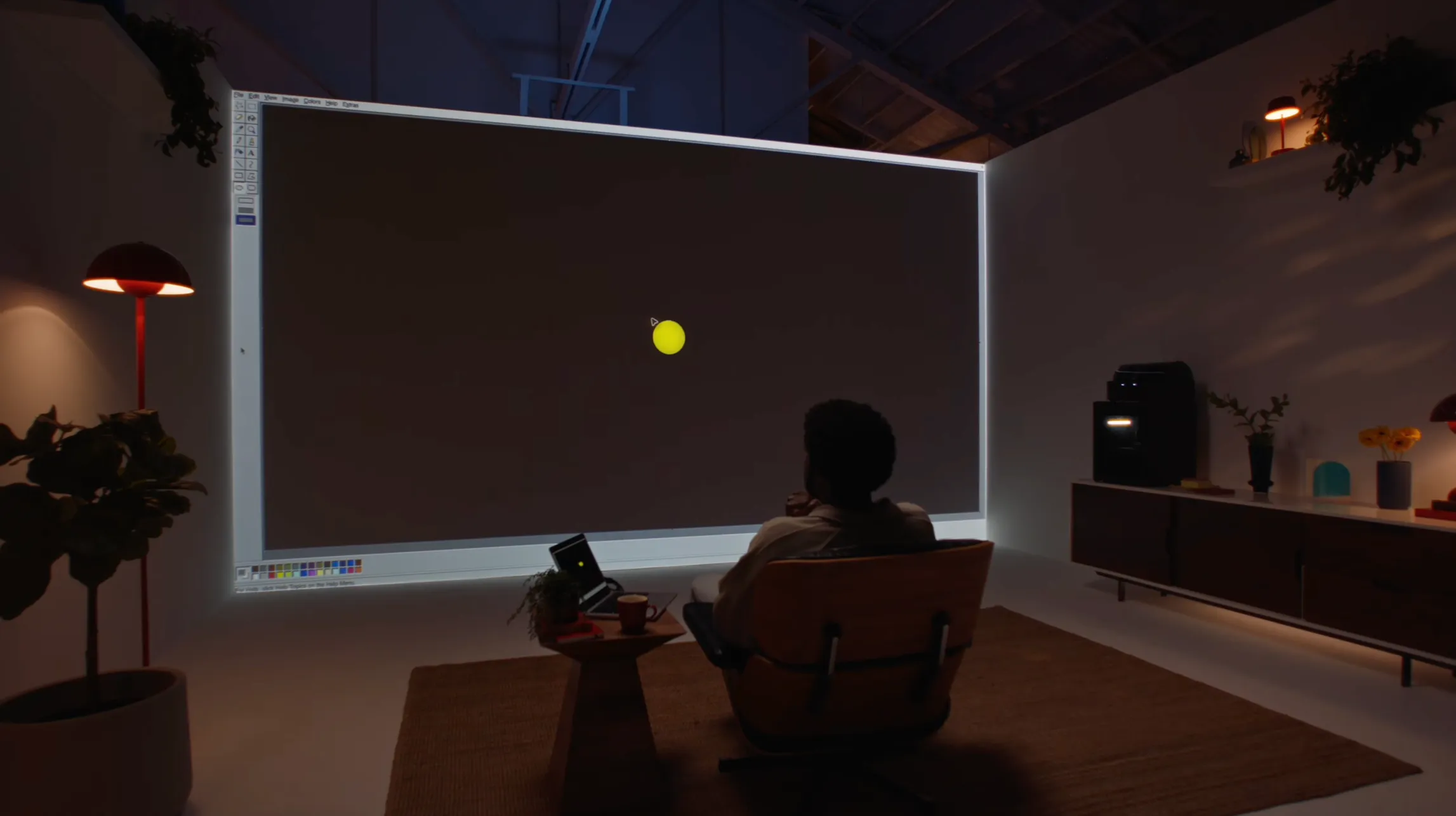A person sits back while GPT-6 Astra operates a paint program on a projected screen during Introducing GPT-6 Astra.